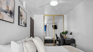 A modern bedroom with a bed, a desk, a chair, and a large mirror. - Cozy Escape | Just Steps from the Beach w. Pool (Carolina)
