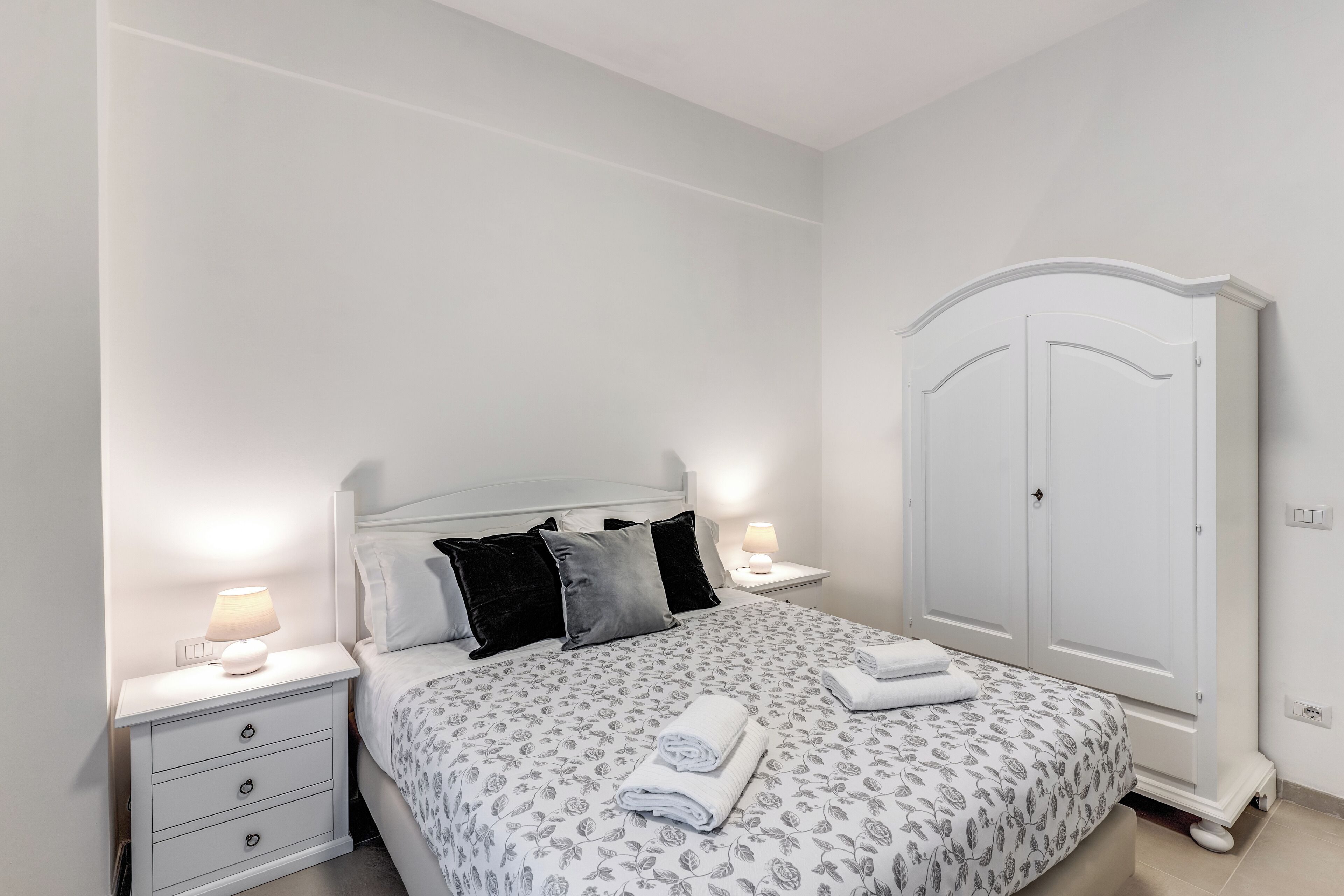 Une chambre à coucher avec un lit, des tables de chevet, une armoire et une lampe.