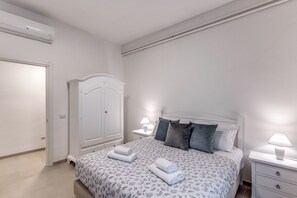 A bedroom with a bed, bedside tables, a wardrobe, and a door.