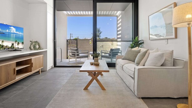 A modern living room with a wooden coffee table, a sofa, a TV, and a large window with a view of the outdoors. - Chic Ground-floor Studio Near Local Cafes (Perth)
