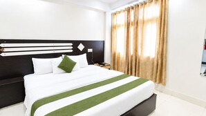 Quarto de hotel com uma cama grande, cabeceira com linhas horizontais, mesa de cabeceira e uma janela com cortinas.
