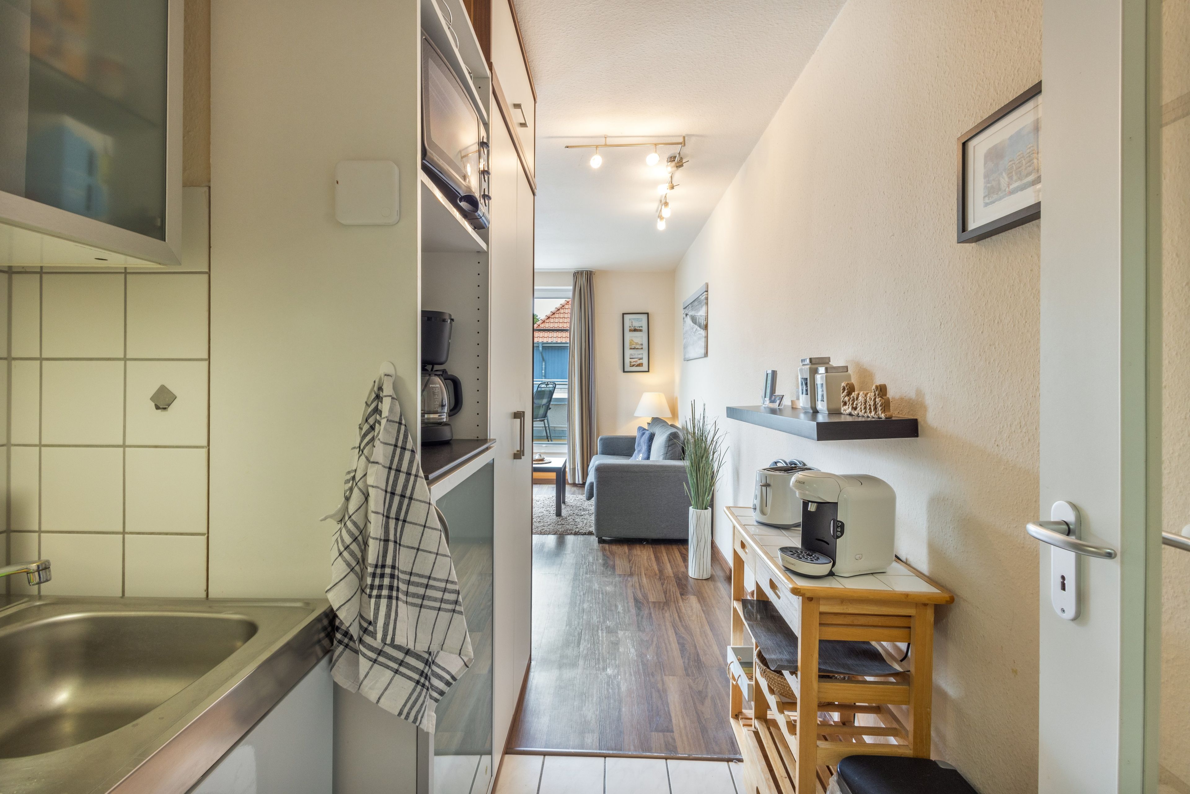 A narrow kitchen with a sink, a coffee machine, and a toaster.