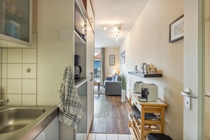 Eine schmale Küche mit Spüle, Kaffeemaschine und Toaster.