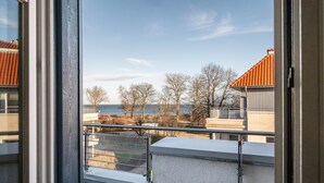 A balcony with a view of the sea, buildings, and leafless trees. - Holiday Apartment 'Sonnendüne Im Dünenblick' with Sea View, Balcony & Wi-Fi (Ostseebad Boltenhagen)