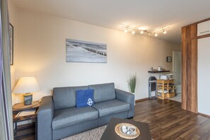 Una sala de estar moderna con un sofá gris, una mesa de centro, una lámpara y un cuadro en la pared.