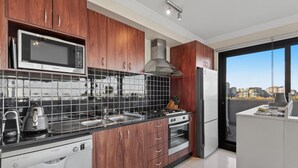 Eine moderne Küche mit Holzschränken, einem Geschirrspüler von Bosch, einer Mikrowelle, einem Herd und einem Kühlschrank.
