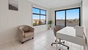 Ein moderner Arbeitsraum mit großem Schreibtisch, bequemem Stuhl und Blick auf die Stadt durch große Fenster.