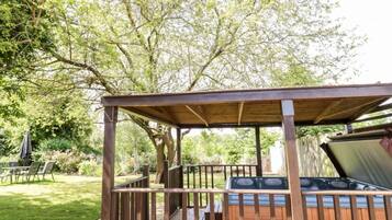 A wooden gazebo with a grill and a barbecue area.