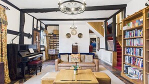 Un salon chaleureux avec un piano, un canapé, une table basse et une bibliothèque.