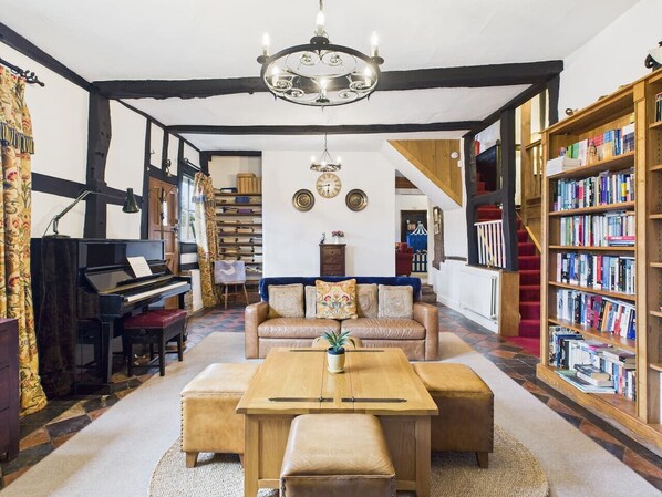Un salon chaleureux avec un piano, un canapé, une table basse et une bibliothèque.
