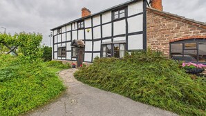 Une maison traditionnelle à colombages, avec un chemin pavé menant à l’entrée.