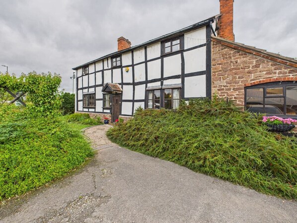 A traditional half-timbered house with a paved pathway leading to the entrance.
