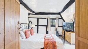 Une chambre à coucher avec un lit, des oreillers, une télévision et une armoire en bois.