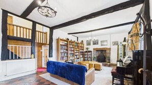 Un salon spacieux avec une grande bibliothèque, un piano et une cheminée.
