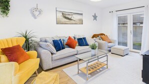 Ein modernes Wohnzimmer mit einer Couch, Sesseln und einem Couchtisch. An der Wand hängt ein Gemälde und eine Stern-Dekoration ist vorhanden.
