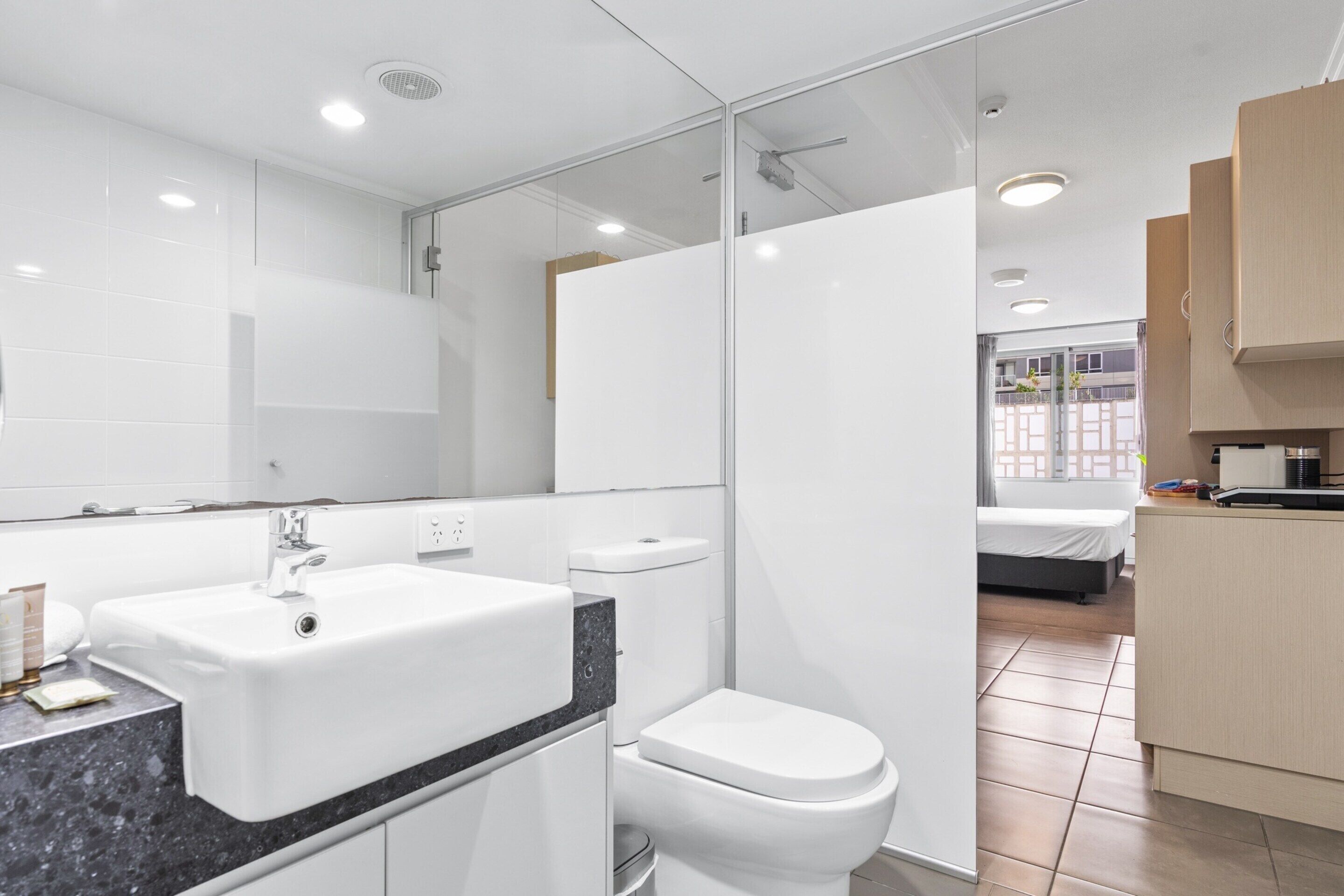 Une salle de bain moderne avec un lavabo, des toilettes et une zone de douche, le tout de couleur blanche.