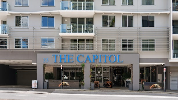 Un hotel de varios pisos con una entrada destacada que indica "THE CAPITOL".