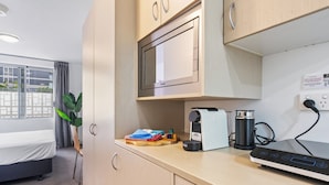 Una kitchenette compacta equipada con microondas, cafetera y toma de corriente.