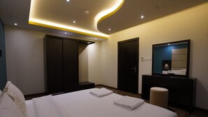 Une chambre d’hôtel moderne avec un grand lit, une coiffeuse avec un miroir et une armoire.