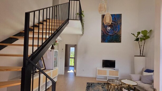 Een moderne woonkamer met een trap, een flatscreen televisie en een groot abstract schilderij.