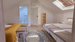 Een slaapkamer met dakraam, een bed, een bankje, een vloerkleed en een kledingkast.