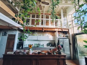A spacious kitchen with high ceilings, wooden beams, and hanging plants. - Chbr 8 pers in Gîte de Charme near Provins (Savins)