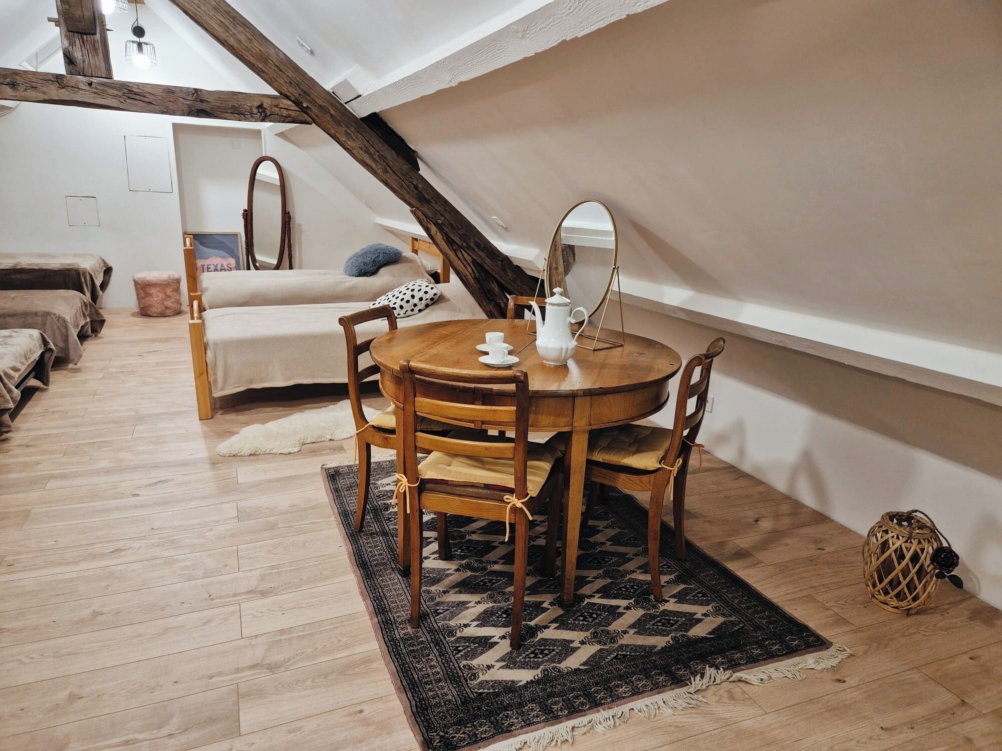 Une chambre à coucher confortable, aménagée en mezzanine, avec une table à manger en bois, un grand miroir et une esthétique rustique.