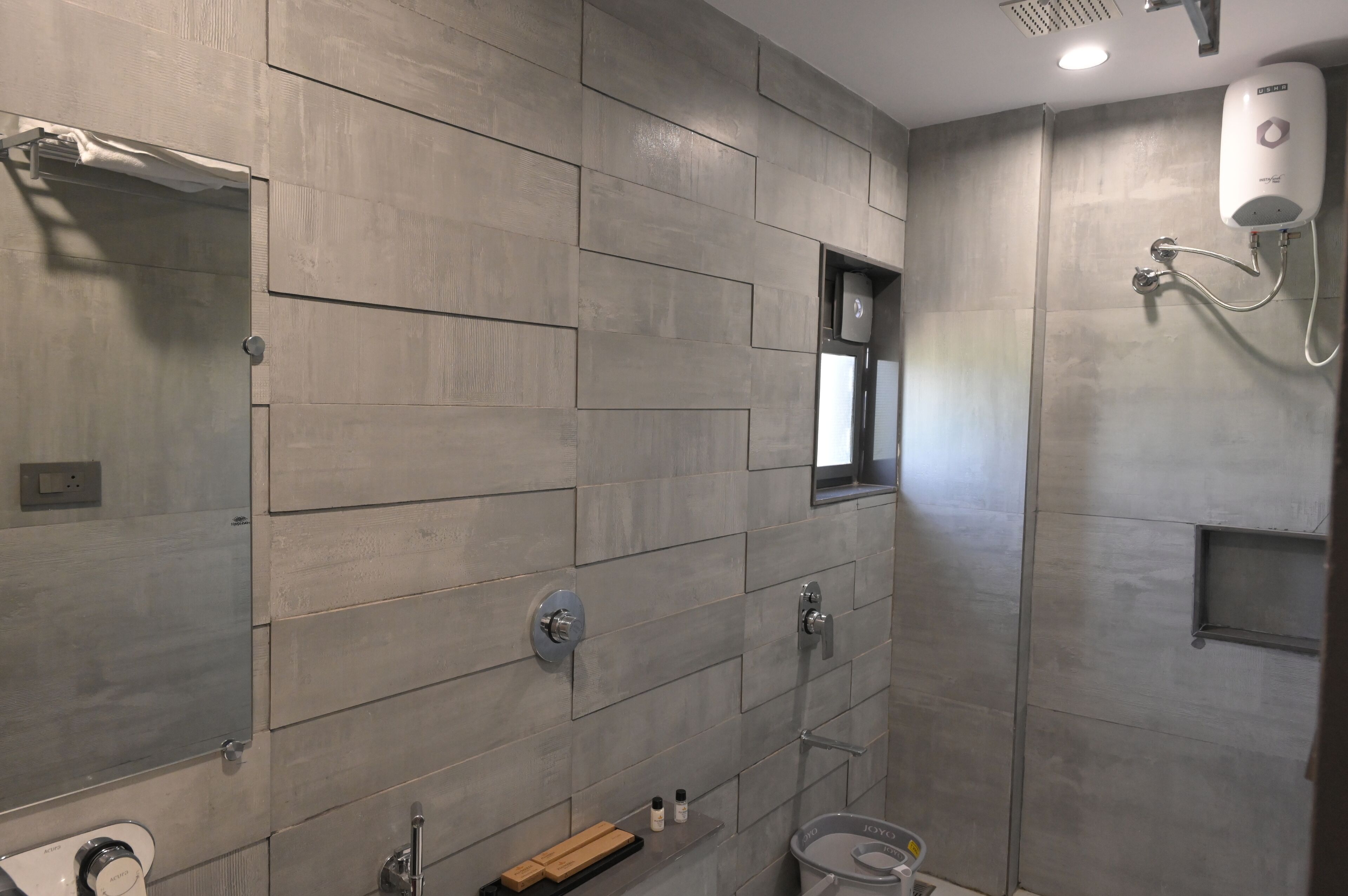 Une salle de bain moderne avec un mur carrelé, une douche, un lavabo et un miroir.