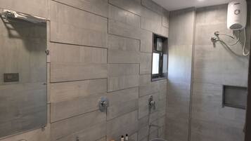 Une salle de bain moderne avec un mur carrelé, une douche, un lavabo et un miroir.