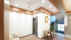 Ein modernes Interieur mit einem Fischgrätparkett, Deckenventilator, einer Couch mit gemusterten Kissen, einer Holz-Akzentwand und einer Treppe zu einer oberen Ebene.