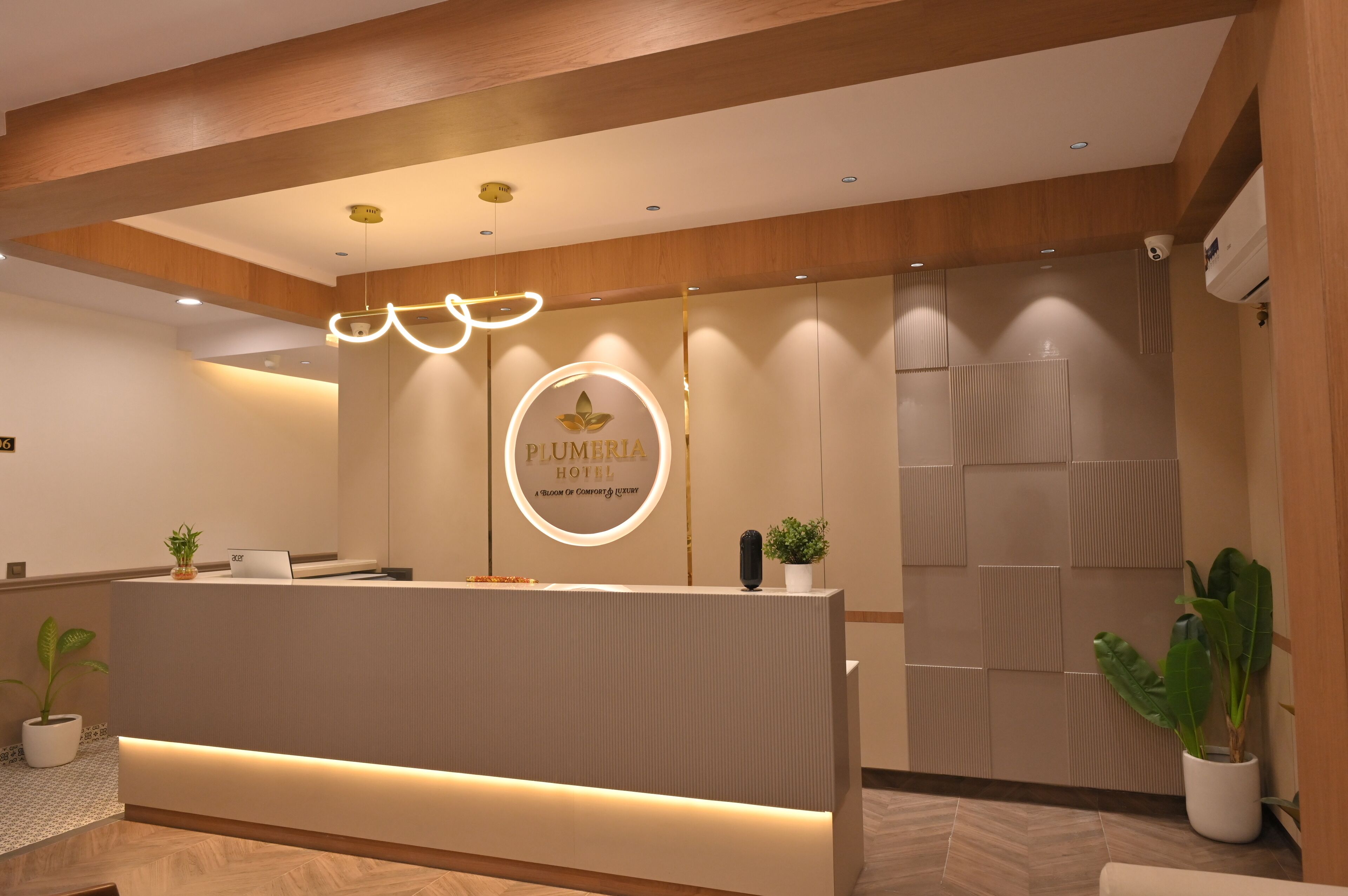 A hotel reception area with a modern design, featuring a reception desk, a circular logo, and a wooden ceiling.