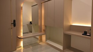 Ein modernes Hotelzimmer mit minimalistischem Design, mit einem großen Spiegel, einer integrierten Garderobe und einer kleinen Sitzecke.