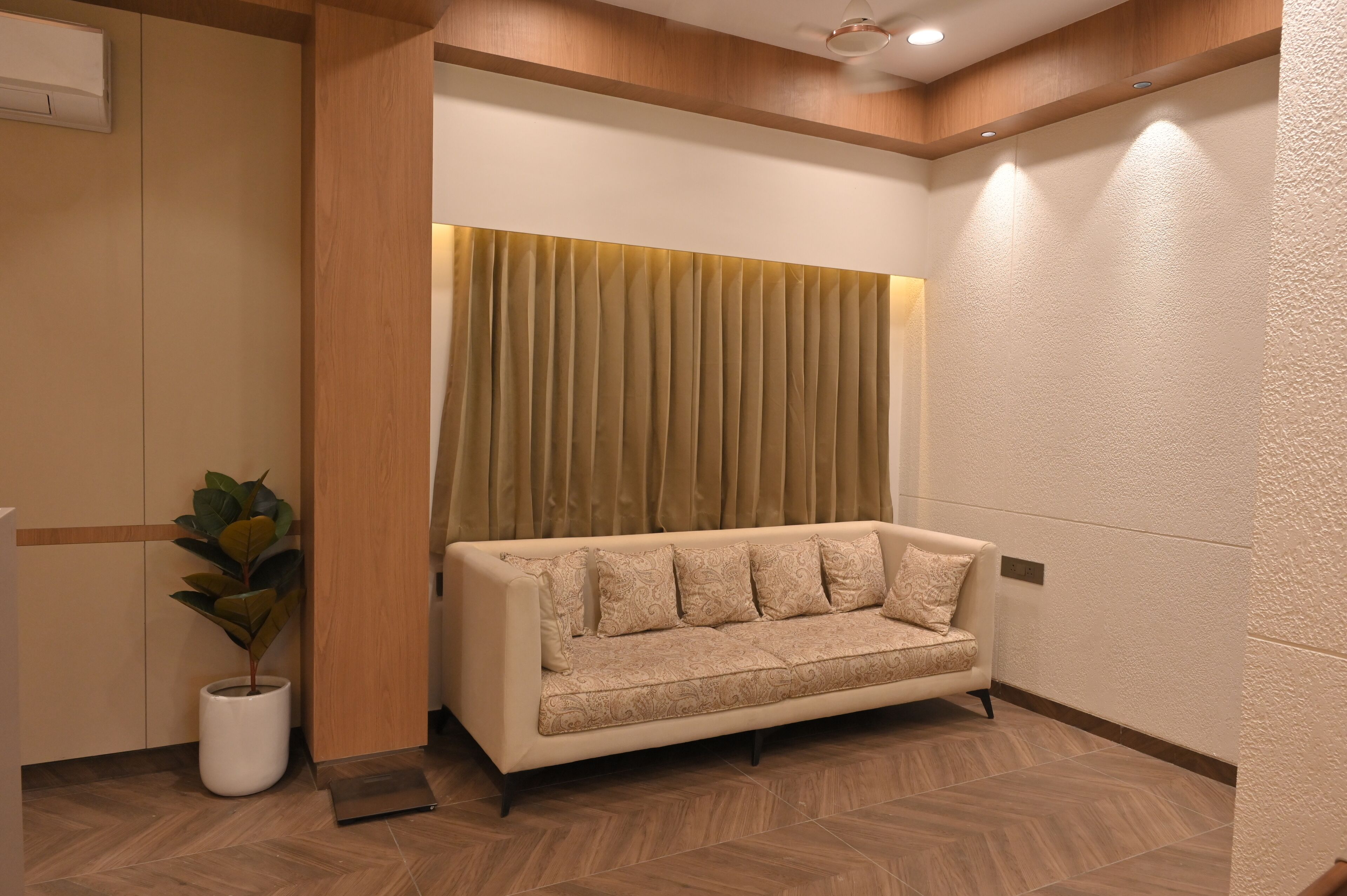 A modern interior with a sofa, a potted plant, and a textured wall.