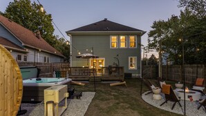 A backyard with a hot tub, outdoor seating, and a fire pit area. - The Nowland Reserve |Sauna, Arcade, Sleeps 14 (Indianapolis)