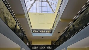 A multi-level atrium with a glass ceiling, ornate railings, and a central decorative feature.