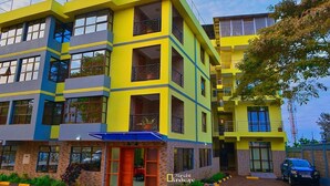 A multi-story building with a yellow and blue facade, featuring balconies and large windows.