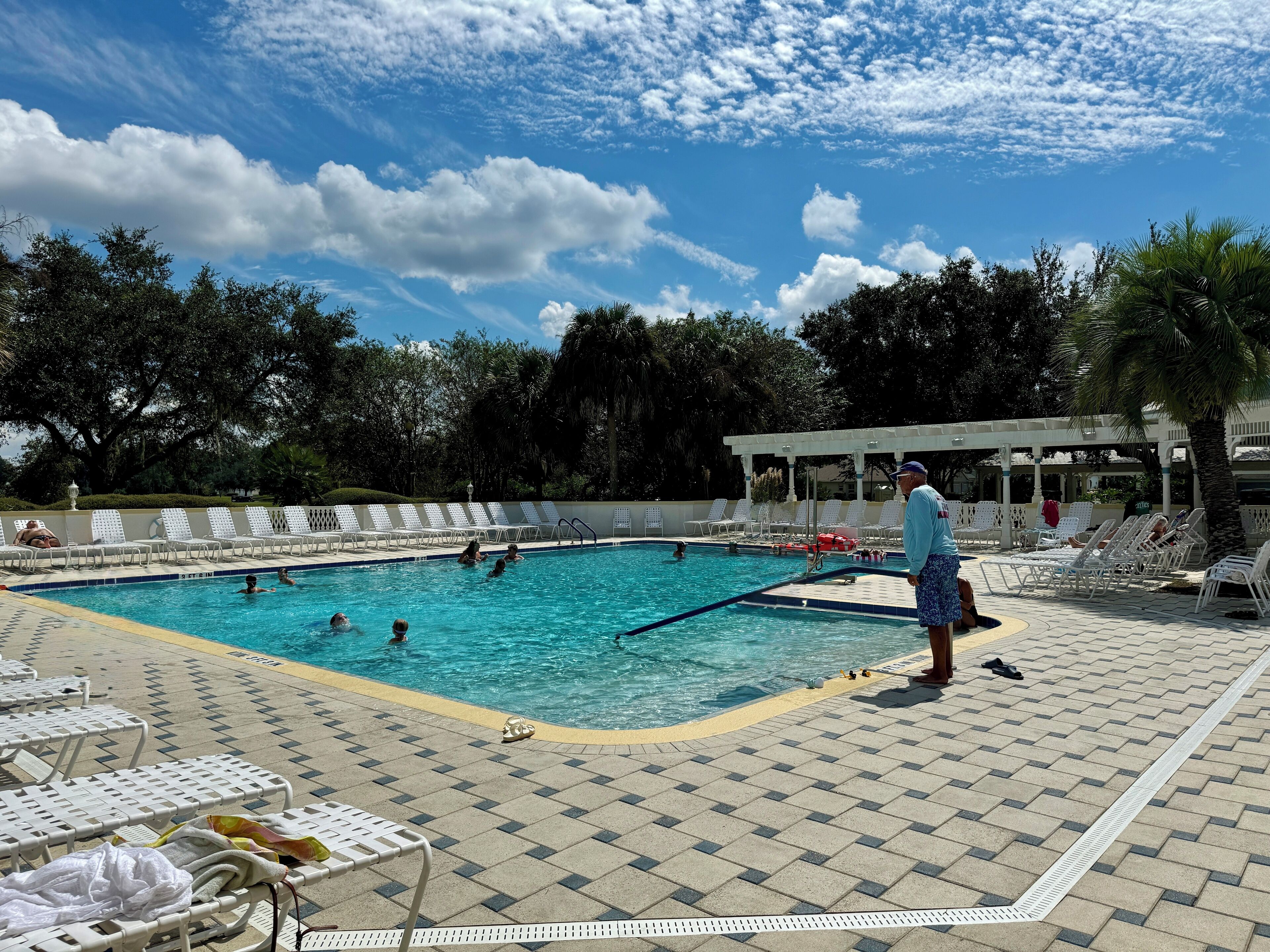 A swimming pool with lounge chairs and a covered area.