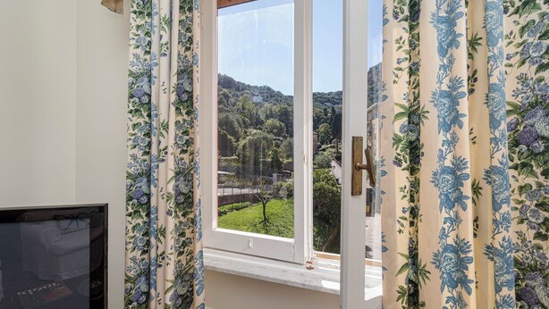 Ein Zimmer mit Fenster und Blick auf eine grüne Landschaft und Hügel.