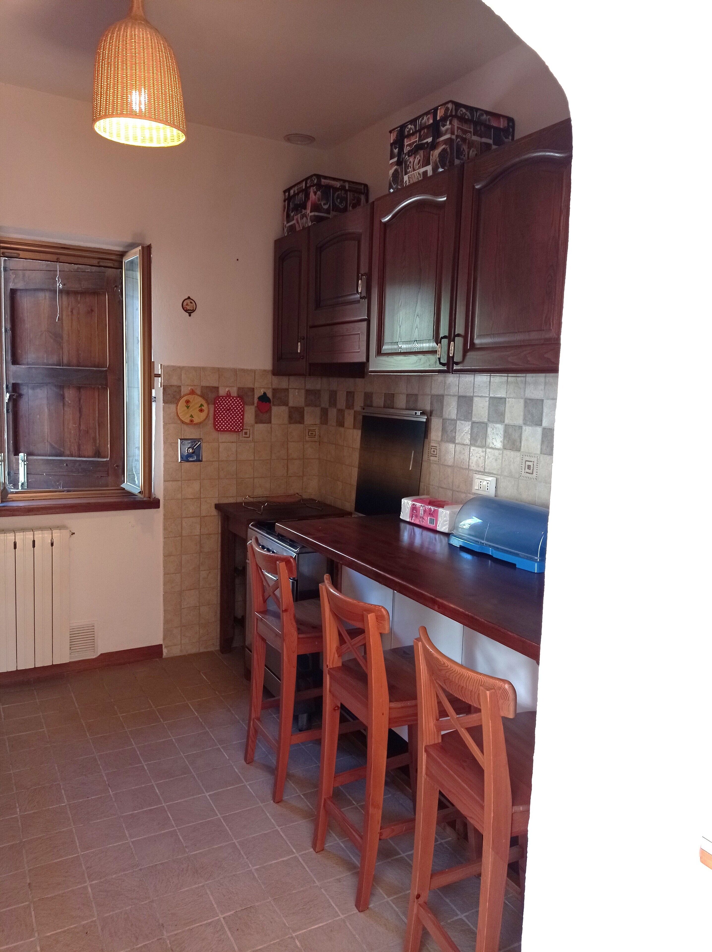 A kitchen with wooden cabinets, a tiled backsplash, a gas stove, and a wooden island with bar stools.