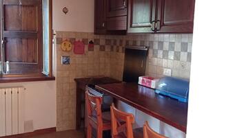 A kitchen with wooden cabinets, a tiled backsplash, a gas stove, and a wooden island with bar stools.
