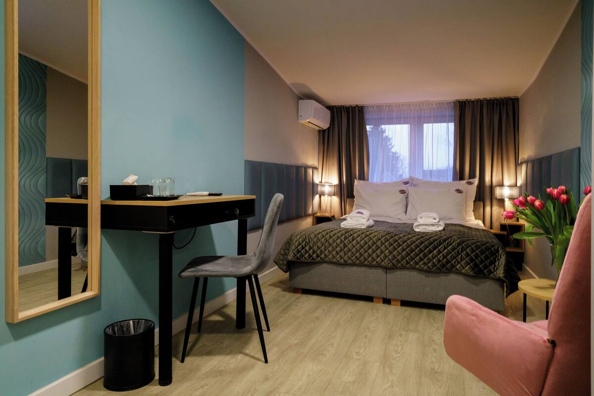 Una camera d'albergo con un letto, una scrivania, una sedia e un tavolino con un vaso di fiori.