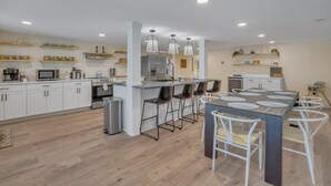 A modern kitchen with white cabinets, a central island with bar stools, and overhead pendant lighting. - Marvelous Manning: 4-Bdr + Studio + Gameroom (Shad Moss village)