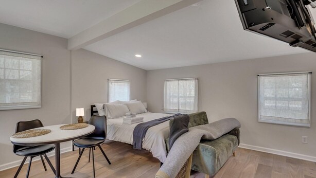 A modern bedroom with a bed, bedside tables, a desk, and chairs. - Cypress Cottage - Cozy Lake Getaway (Shad Moss village)