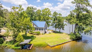 A house with a blue roof, surrounded by trees and a lake. - Tie One On! at 4 Bdr Waterfront Lake Marion (Manning)