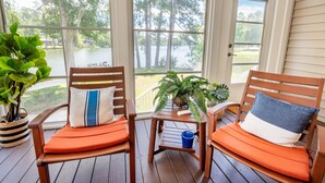 A wooden deck with two chairs and a small table, overlooking a lake with trees. - Tie One On! at 4 Bdr Waterfront Lake Marion (Manning)