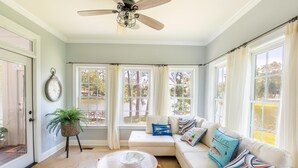A sunlit room with a white sofa, a round table, and a ceiling fan. - Tie One On! at 4 Bdr Waterfront Lake Marion (Manning)
