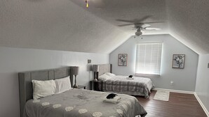 A bedroom with a large bed, two smaller beds, a ceiling fan, and artwork on the walls. - Bright & Roomy 4BR/5-Bed Home Just Off Dorchester (North Charleston)