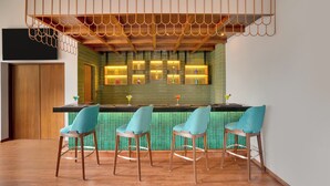 A modern bar area with wooden ceiling and green-tiled backsplash, featuring bar stools and illuminated shelves. - Lemon Tree Premier Thiruvananthapuram (Thiruvananthapuram)