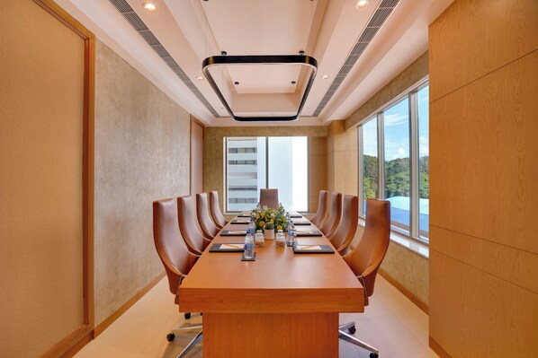 Une salle de conférence dotée d’une longue table, de chaises et offrant une vue sur l’extérieur grâce à de grandes fenêtres.