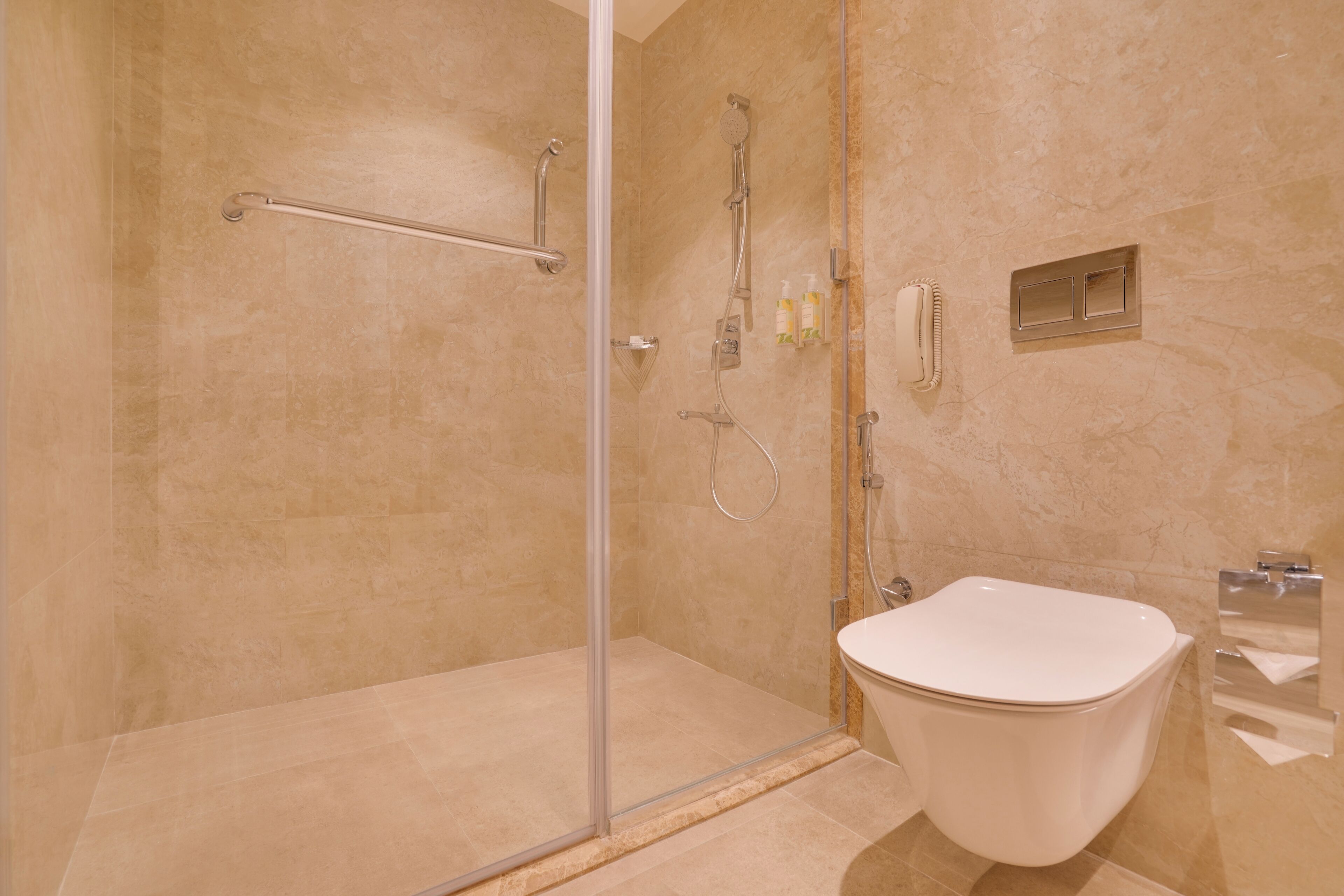 A modern bathroom with a glass-enclosed shower, a white toilet, and a marble-tiled floor.